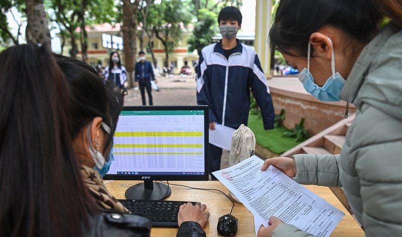 giáo viên kiểm tra danh sách học sinh trước khi tiêm vaccine Covid19